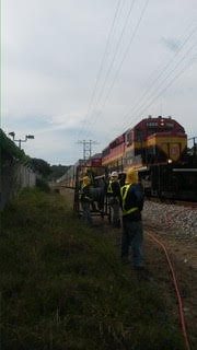 Personal técnico trabajando junto a vía ferroviaria Panamá Colón en proyecto de fibra óptica